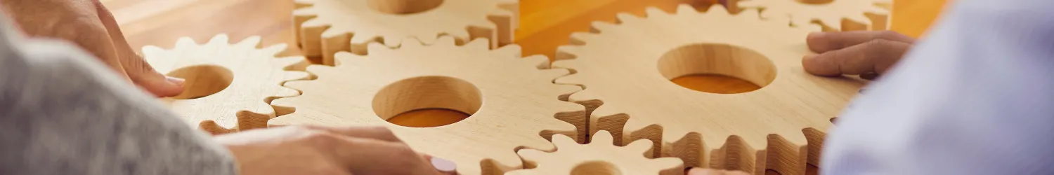 People placing wooden gears together.