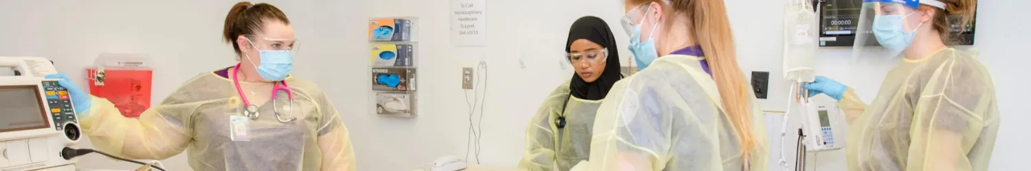 Students working on a dummy in a mock hospital room.