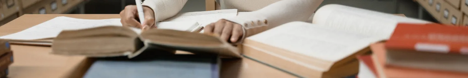 Woman at a desk with open books, studying.